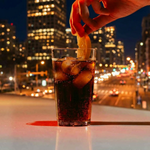 Vaso de plastico de 50cl de policarbonato en un bar con bebida dentro y hielo y una mano cogiendo el limon